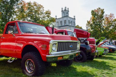 21 Eylül 2025 - Doğu Gwillimbury, Ontario, Kanada: Sharon Temple Araba Fuarı 'nda ön planda kırmızı bir Chevrolet kamyonet ile sergilenen eski klasik arabaların listesi. Koleksiyoncular, meraklılar ve restorasyon ile açık hava klasik otomobil etkinliği