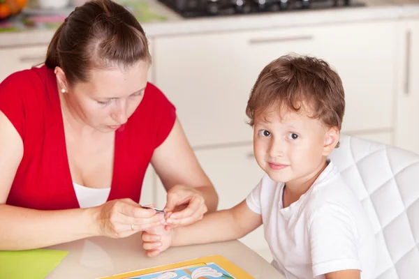 Una giovane donna taglia le unghie del bambino a casa — Foto Stock