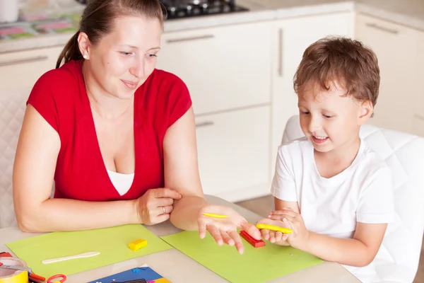 Eine junge Frau mit einem Sohn, der Spaß beim Spielen in Ton hat lizenzfreie Stockfotos