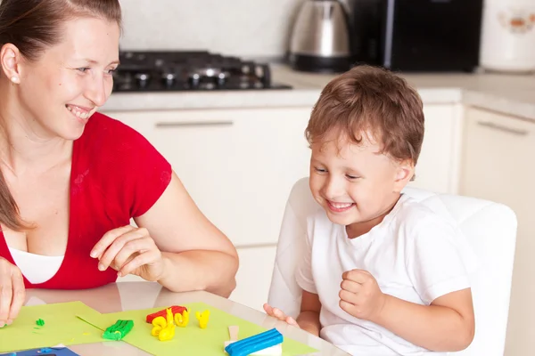 Una giovane donna con un figlio che si diverte giocando in argilla Foto Stock