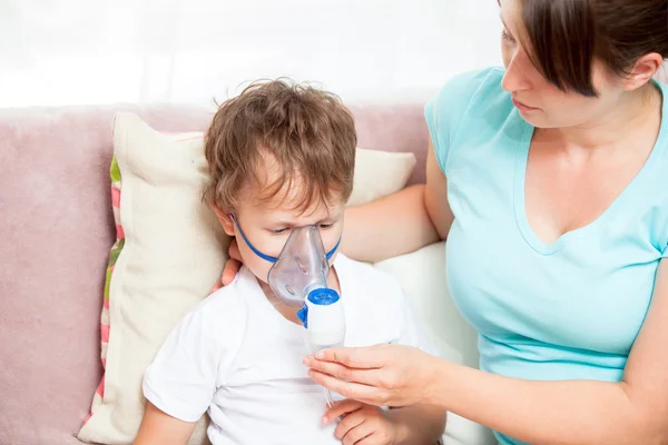 Jovem mulher com filho fazendo inalação com um nebulizador em casa — Fotografia de Stock