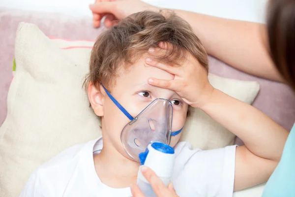 Mujer joven haciendo inhalación con un hijo nebulizador y toca su frente —  Fotos de Stock