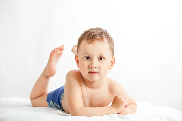 Pojken i blå shorts liggande på vit bakgrund — Stockfoto