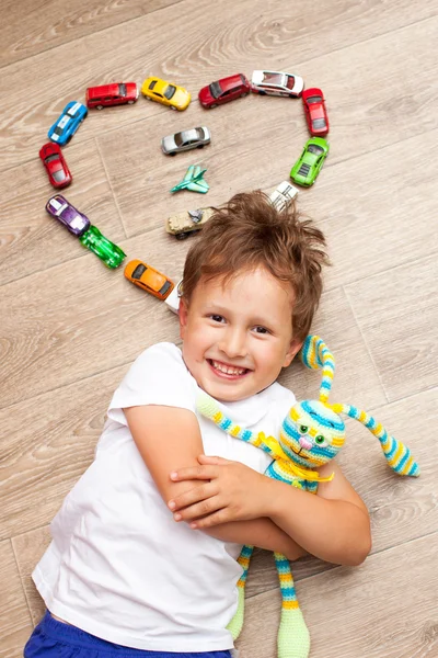 Niño feliz jugando en el suelo con coches de juguete —  Fotos de Stock