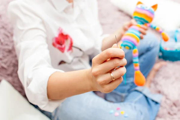 Jeune femme est engagée dans la broderie, pour coudre des jouets amigurumi jambe — Photo