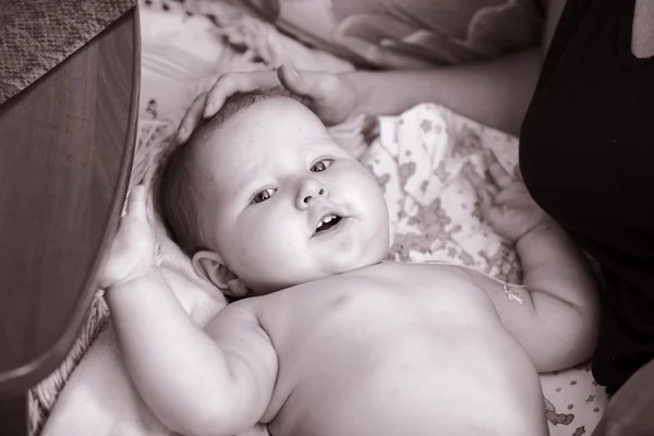 Das Kind liegt auf dem Bett neben der Mutter — Stockfoto