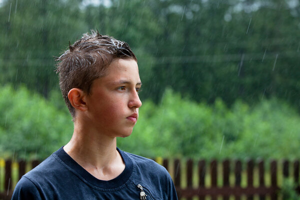 A teenager stands in the rain