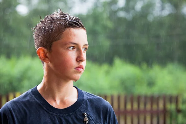 Um adolescente está na chuva — Fotografia de Stock