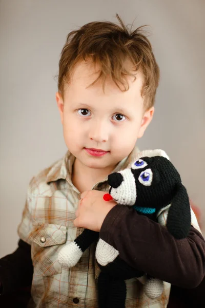 Un niño con un perro de juguete de punto en las manos de —  Fotos de Stock