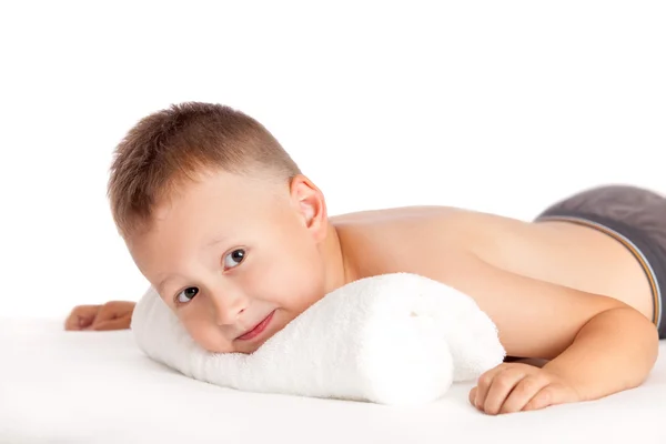 Niño feliz acostado en una mesa de masaje esperando un masaje —  Fotos de Stock