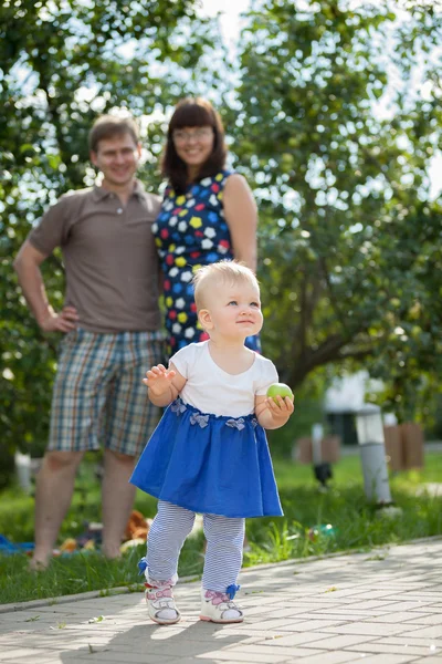 Молода щаслива родина, що йде в парку вздовж шляху зі своєю маленькою донькою — стокове фото