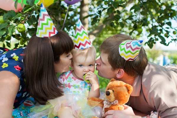Ευτυχείς γονείς σε μια εορταστική καλύμματα μωρό μου φιλί στο μάγουλο — Φωτογραφία Αρχείου