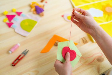 Kadınların elleri keçeden güneş yapıyor. Tahta bir masada dikiş işi için aksesuarlar. Çocuklar ve yetişkinler için bahar ya da yaz el sanatları fikri. Oda dekorasyonu için yaratıcı DIY. Yukarıdan görünüm.