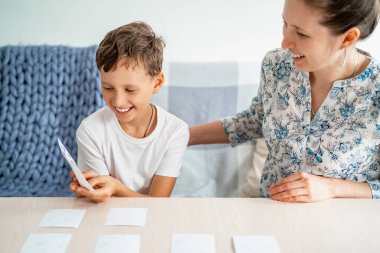 7 yaşındaki bir çocuk evde hafıza ve ilgi geliştirmek için annesiyle hafıza tahtası oyunu oynuyor. Çocuk bilgi kartlarıyla oynuyor, annemle vakit geçirmek eğlenceli. Renkler ve dil öğreniliyor.