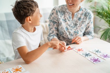 7 yaşındaki bir çocuk evde hafıza ve ilgi geliştirmek için annesiyle hafıza tahtası oyunu oynuyor. Çocuk bilgi kartlarıyla oynuyor, annemle vakit geçirmek eğlenceli. Renkler ve dil öğreniliyor.