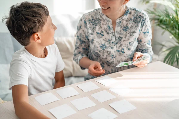 7-year-old boy plays a memory Board game with his mother to develop memory and attention at home. The child plays with the flash cards, fun to spend time with my mother. Learning colors and language.