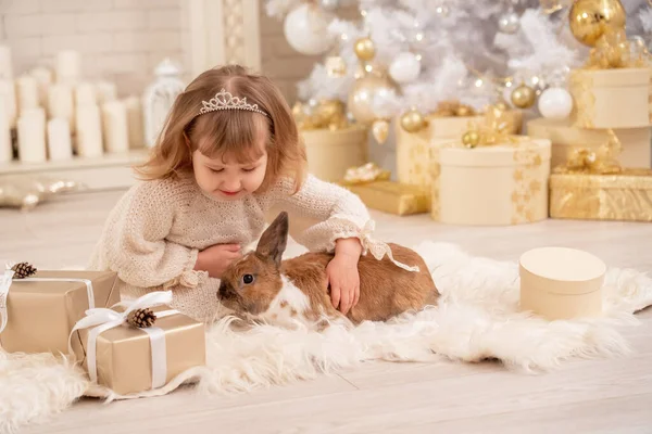 티아라를 귀엽고 소녀가 크리스마스 근처의 부드러운 양탄자에 크리스마스 장식을 벽난로가 — 스톡 사진