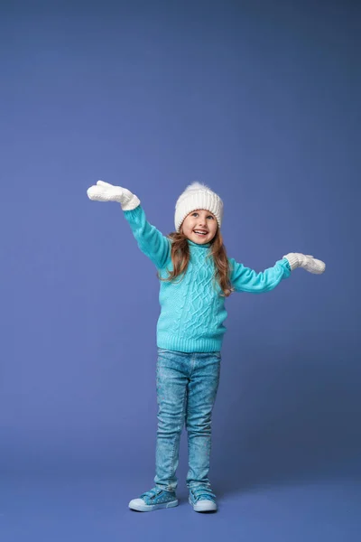 快乐的小女孩4岁 金发碧眼 头戴针织帽衫 头戴手套 笑容满面 站在紫丁香的背景上 假日周末 — 图库照片