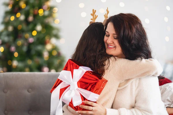圣诞快乐 节日快乐 快乐的妈妈和女儿拥抱在一起 把圣诞礼品盒放在装饰着花环的圣诞树上 复制空间 — 图库照片
