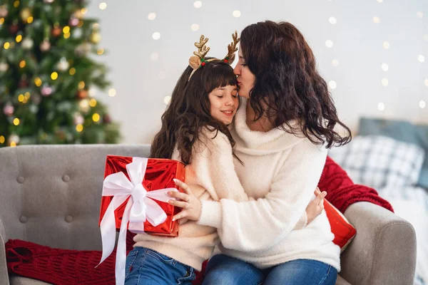 圣诞快乐 节日快乐 快乐的妈妈和女儿拥抱在一起 把圣诞礼品盒放在装饰着花环的圣诞树上 复制空间 — 图库照片