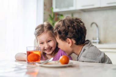 Paskalya için hazırlanıyorum. Komik çocuk ve kız masaya oturup yumurta boyarlar. Çocuklar yumurta rengini alana kadar bekler ve sürpriz ve zevkle renkleri seyrederler..