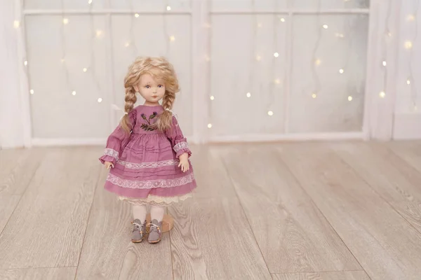 An interior doll with a human face, made by hand from textiles, in a retro style, stand on a light background garland lights. creating dolls for the holiday. an exclusive gift. Companion Doll