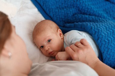 Mutlu genç kadın anne sütüyle besleniyor ve bebeğe sarılıyor. Bir anne yeni doğmuş bir bebeği yatakta yatarken emziriyor. Yeni doğan emzirme kavramı. Çocuk yatmadan önce süt içer. Yan görünüm.