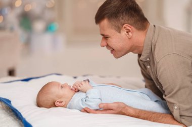 Sevgi dolu bir baba, bebeğin bezini değiştirir, konuşur, oynar, günlük bakım yapar. Bebek battaniyesinde yatan yeni doğmuş bebeği değiştiren bir babanın yakın çekimi..