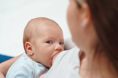Bebek emzirirken annesinin gözlerinin içine bakıyor. Annesinin memesinden süt emen bir çocuğun yakın plan portresi. Bir kadın bebeğini kollarında emziriyor. annelik kavramı.