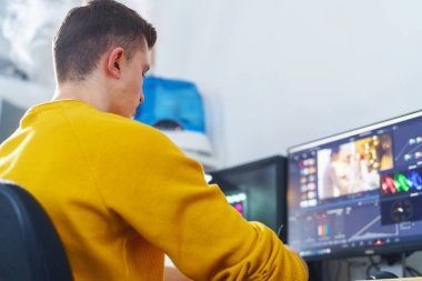 Yan görüş, erkek-kameraman kalem tableti ve özel bir program kullanarak evdeki bilgisayarın önünde video işleme yapıyor. Video düzenleme. Blog yazıyorum. Serbest çalışan biri. Uzaktan kumanda. Eğitim yeniden başlatılıyor