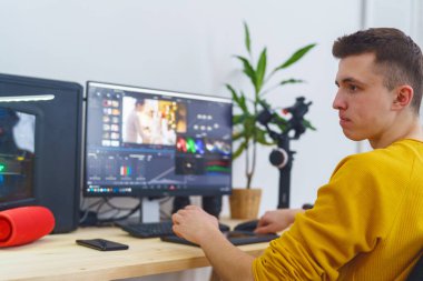 Yan görüş, erkek-kameraman kalem tableti ve özel bir program kullanarak evdeki bilgisayarın önünde video işleme yapıyor. Video düzenleme. Blog yazıyorum. Serbest çalışan biri. Uzaktan kumanda. Eğitim yeniden başlatılıyor