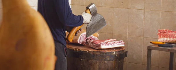 The butcher Cuts Meat With an axe. Pork carcass in the butcher shop of the cutting shop. Meat products. A product of animal origin. Part of the animal carcass.