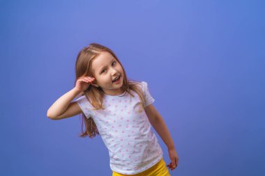 Çekici küçük kız elini kulağına koyup gülümserken mor bir arka planda söylentiler ya da dedikodular duyuyor. Çocuk kulak misafiri
