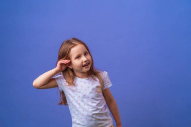 Çekici küçük kız elini kulağına koyup gülümserken mor bir arka planda söylentiler ya da dedikodular duyuyor. Çocuk kulak misafiri