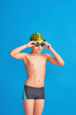 Mavi arka planda mayo, gözlük ve mayo takan küçük bir yüzücü. Çocuk bardaklarını ayarlar, su gider. Oğlan spor okulunda okuyor, yüzme öğreniyor. Yüzme gözlükleriyle ilgili sorunlar