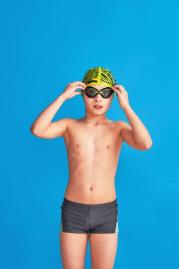 Mavi arka planda mayo, gözlük ve mayo takan küçük bir yüzücü. Çocuk bardaklarını ayarlar, su gider. Oğlan spor okulunda okuyor, yüzme öğreniyor. Yüzme gözlükleriyle ilgili sorunlar