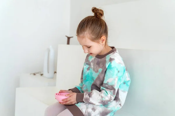 穿着时髦衣服的迷人的微笑的小女孩坐在台阶上玩着一个有教育意义的游戏 一个在明亮的房间里放着球的迷宫 发展逻辑思维 培养心智的概念 — 图库照片