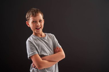 Gülümseyen sevimli bir çocuğun portresi, kendine güvenen bir gülümseme, siyah bir arka planda izole edilmiş, neşeli bir çocuk, tasasız bir çocukluk. Boşluğu kopyala.