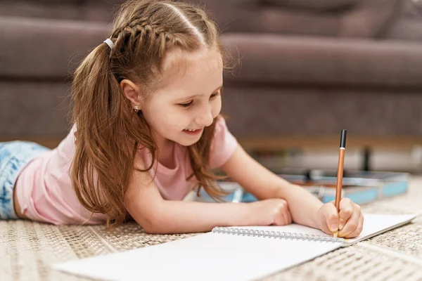 Маленькая Милая Белая Девочка Рисует Альбом Цветными Карандашами Лежащий Полу — стоковое фото