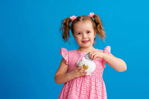 Poupança Feliz Uma Menina Fofa Com Banco Porquinho Fundo Azul — Fotografia de Stock