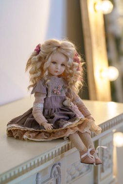 Dost Bebek. Eski moda tekstil el yapımı insan yüzlü oyuncak bebek arka plandaki çelenk ışıklarına karşı şöminenin üzerinde oturuyor. Tatil için oyuncak bebek yapıyorlar. Özel bir hediye..