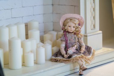 Dost Bebek. Eski moda tekstil el yapımı insan yüzlü oyuncak bebek arka plandaki çelenk ışıklarına karşı şöminenin üzerinde oturuyor. Tatil için oyuncak bebek yapıyorlar. Özel bir hediye..