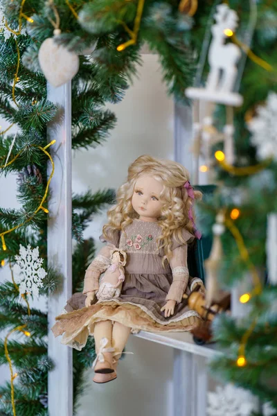 Tekstil el yapımı, insan yüzlü iç kukla, retro tarzda, ışıkların arka planında bir rafta oturur. Tatil için oyuncak bebek yapıyorlar. Özel bir hediye. Dost Bebek!