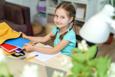 Sevimli mutlu öğrenci ofis malzemelerini sırt çantasına koyar. Okul için hazırlık. Okula dönelim. Bir okul sırt çantasının kendiliğinden montajı.