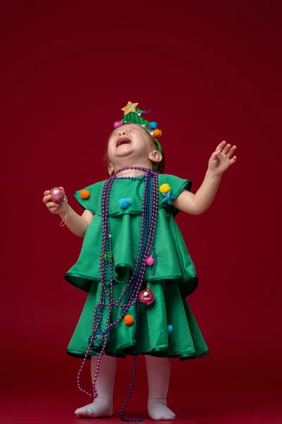 Egy Karácsonyfa Jelmezes Kislány Áll Piros Háttérben Gyerek Nagyon Zaklatott — Stock Fotó