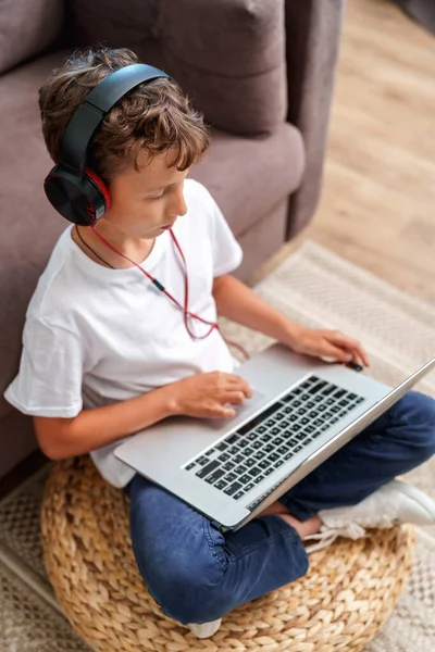 Entusiastisk Pojke Med Hörlurar Och Laptop Sitter Golvet Nära Soffan — Stockfoto