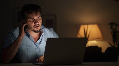 Genç erkek işadamı geceleri evde dizüstü bilgisayarda çalışıyor. Ev ofisinden çalışıyor, internetten çalışıyor. İnternet bağımlılığı ya da gece geç saatlere kadar çalışan bir adam. Düşünceli adam gece geç saatlere kadar merkez büroda çalışıyor.