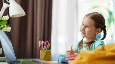 Özenli küçük kız öğretmeniyle video görüşmesi yapmak için dizüstü bilgisayar kullanıyor. Çocuk uzaktan öğrendiği için mutlu. Öğrenci kız bilgi almaktan mutlu. E-Eğitim Mesafesi Ev Öğrenimi.