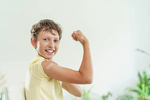 Mutlu Gülümseyen Aşılanmış Çocuk, Coronavirus aşısı aşısı yaptıktan sonra elini yamayla gösteriyor. Koronavirüse karşı Çocuk Aşısı Reklamı