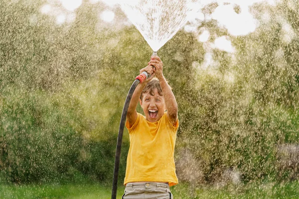 Happy Boy Spettert Speelt Met Tuinslang Met Sproeier Bij Zonsondergang — Stockfoto